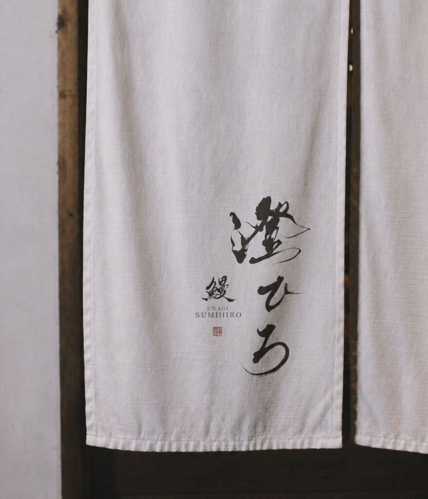 Japanese calligraphy logo design displayed on a noren curtain for an unagi restaurant